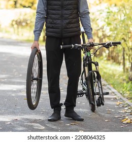 A Man Holds A Broken Bicycle In His Hands. Close Up.