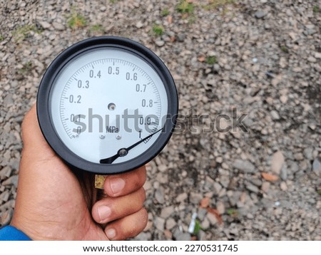 A man holds a broken pressure gauge or mechanical manometer, performs maintenance and replaces instruments