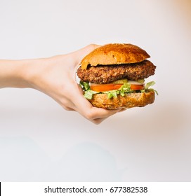 Man holds burger with hands on white background. top view