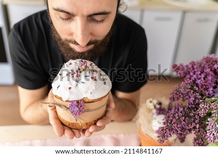 man holds close-up of an Easter cake in his hands. Traditional pastries for happy Easter. Strong men hands gently hold a festive cupcake decorated with flowers