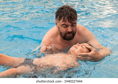 A Man Holds A Disabled Child During Aquatic Therapy In A Swimming Pool.