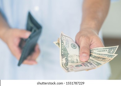 A man holds dollars in his hands. paying in cash, people, business, finances and money concept. - Powered by Shutterstock