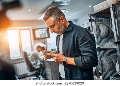 A man holds an electronic microchip while standing in the office. Development of microchips, technology.