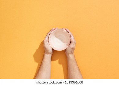 Man holds an empty bowl in his hands over orange