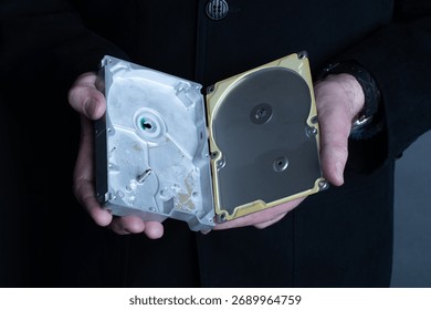 A man holds an empty opened hard disk in his hands. Identity theft or corporate secret concept.