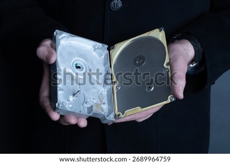 A man holds an empty opened hard disk in his hands. Identity theft or corporate secret concept.