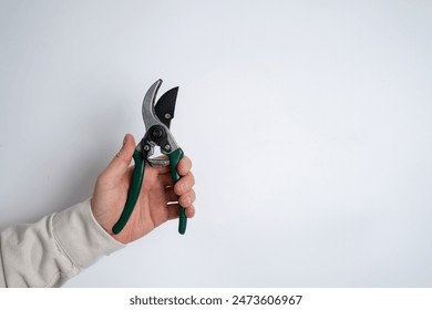 A man holds a garden pruner in his hands. A set of gardening tools for caring for plants in the garden or at home. Florist and gardening care concept - Powered by Shutterstock