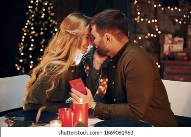 Man holds gift box. Makes proposal mo marry him. Young lovely couple have romantic dinner indoors together. - Powered by Shutterstock