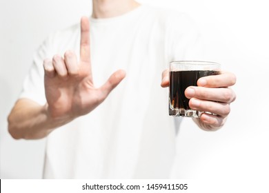 Man Holds A Glass Of Cola And Showing Attention Sign By Forefinger On A White Background.  Fizzy Soda Black. Fast Food Drink. Unhealthy. No Sugar