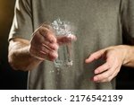 A man holds a glass of water with a shaking hand. The concept of parkinson