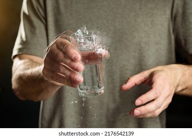 A man holds a glass of water with a shaking hand. The concept of parkinson's disease and tremor.