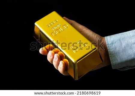 a man holds gold on a black background. Present 1000 g of fine gold bars