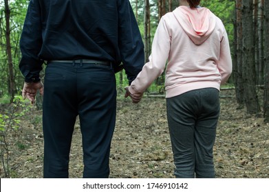 A man holds the hand of a teenage girl in the woods. The concept of kidnapping and child trafficking. Close up.