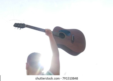 The man holds his guitar up.