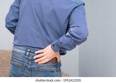 A Man Holds His Hand In The Lumbar Region In Pain And Suffering. 