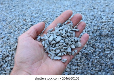 man holds in his hand a sample of stone gravel or pebbles of one size. Marble white gravel and gray brown pebbles straight from the quarry.