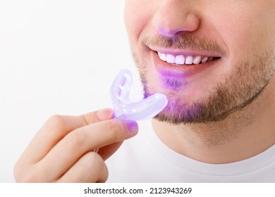 A Man Holds In His Hand An Ultraviolet Lamp For Home Teeth Whitening. A Snow-white Smile After Bleaching.