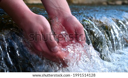 A man holds his hand (washes his hands) in the fountain (water), clearing them of dirt, and holding the water of the waterfall in the length of his hand. Concert of: Feel the water, Slow motion.
