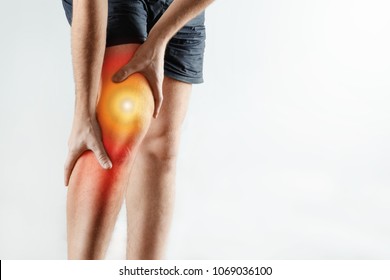The Man Holds His Hands To The Knee, Pain In The Knee Highlighted In Red, Arthritis, Arthrosis, Meniscopathy, Tendonitis. Light Background. The Concept Of Medicine, Massage, Physiotherapy, Health.