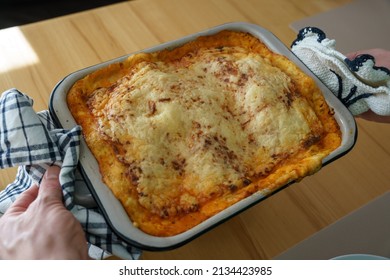 A Man Holds A Homemade Lasagna In A Casserole Dish. Closeup, At Home. 