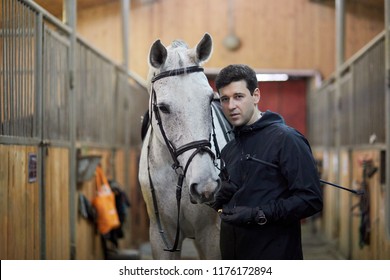 Man holds horse by bridle in riding stables. - Powered by Shutterstock