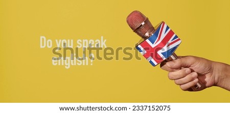 a man holds a microphone patterned with the union jack, the flag of the united kingdom, and the question do you speak english on a yellow background, in a panoramic format to use as web banner