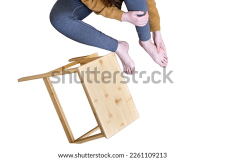 A man holds on to his injured leg after falling from a wooden ladder, isolated on a white background. Safety issues at work at height due to disruption to work at home