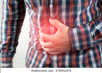 A man holds on to his stomach. Pain in the abdominal cavity. The concept of diseases of the stomach and digestive system.