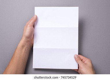 Man Holds An Open Blank Letter Mock-up And On A Gray Background