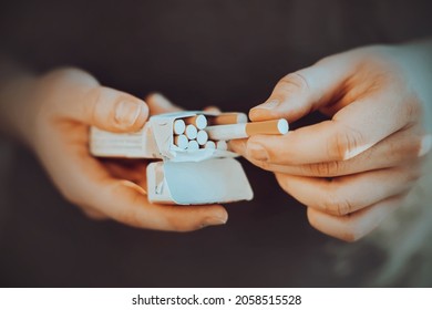 A man holds an open pack of cigarettes in his hands and takes a cigarette out of it to light it. Nicotine addiction. The habit of smoking. - Powered by Shutterstock