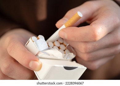 Un hombre sostiene un paquete de cigarrillos en sus manos, con una mano cerrada con un cigarrillo. Persona con un mal hábito que no es saludable