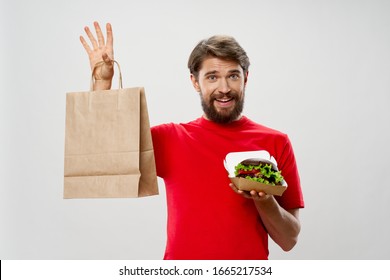 A man holds a paper box with a hamburger in paper bags