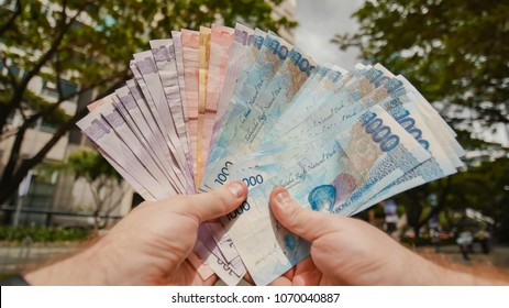 A man holds Philippine money bills in his hands.