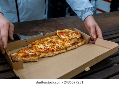 A man holds a piece of pizza in his hand. Delivery of pizza. Take away. - Powered by Shutterstock