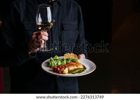 a man holds a plate of grilled fish