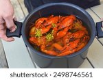 A man holds a pot of crayfish boiled in beer and dill at a crayfish party in Sweden