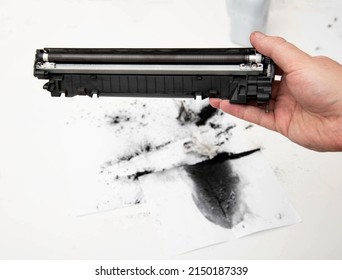 A man holds a refilled laser printer cartridge in his hand against the background of using old toner. Refilling the cartridge at home
