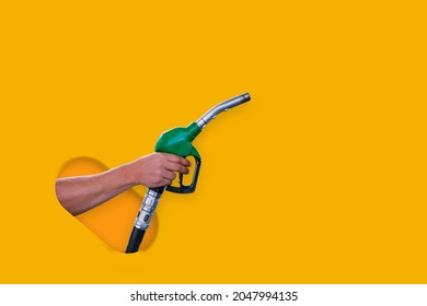 Man holds a refueling gun in his hand for refueling cars isolated on yellow background. Gas station with diesel and gasoline fuel close-up