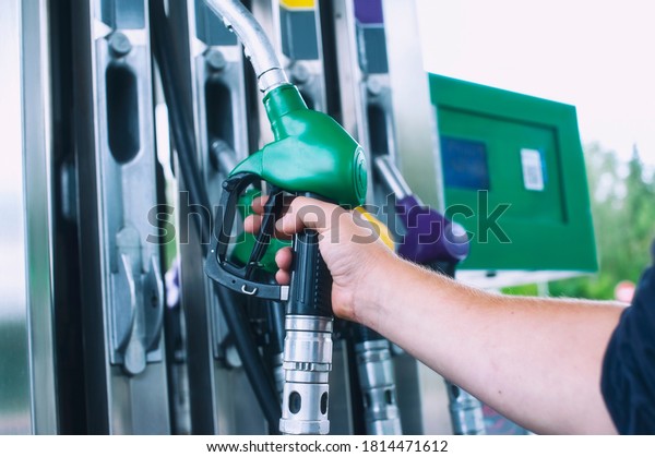 Man holds a\
refueling gun in his hand for refueling cars. Gas station with\
diesel and gasoline fuel\
close-up