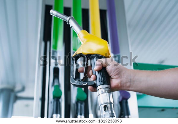 Man holds a\
refueling gun in his hand for refueling cars. Gas station with\
diesel and gasoline fuel\
close-up