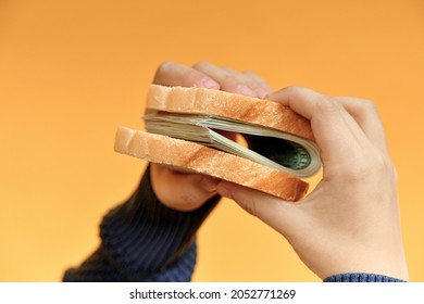 A Man Holds A Sandwich Made Of Money In His Hands. Income, Success And Stability Concept.