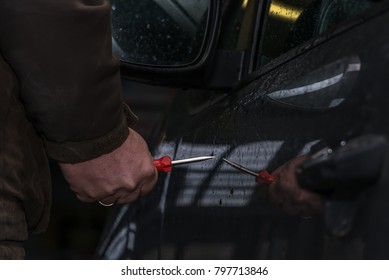 A Man Holds A Screwdriver In His Hand And Wants To Scratch The Car Paint. He Retaliates From Jealousy. Concept: Vandalism And Crime