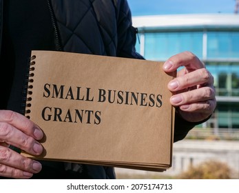 Man Holds Small Business Grants Sign On The Street.