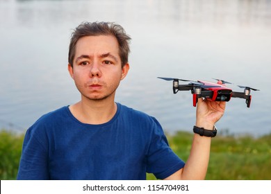 man holds small compact red drone 
