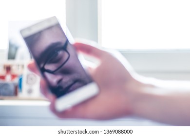 Man Holds A Smart Phone In His Hand, Reflection Of His Face On The Display