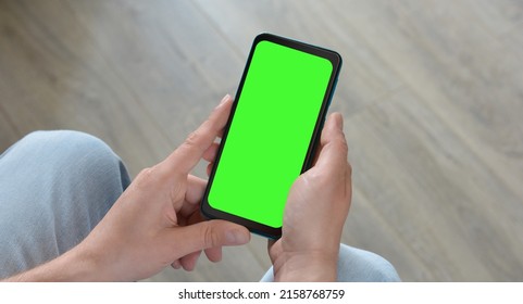 A man holds a smartphone with a green screen.Mockup. Copy space for text - Shutterstock ID 2158768759