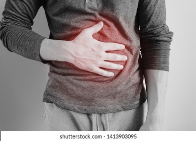 A man holds the stomach. The pain in his chest. Heartburn. Stomach hurts. Sore point highlighted in red. Closeup. Isolated - Shutterstock ID 1413903095