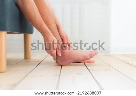 Man holds swollen ankle. Closeup.
