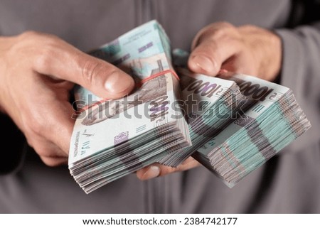 Man holds two bundles of hryvnia in her hand. Ukrainian money. Business concept. 1000 hryvnia banknotes.