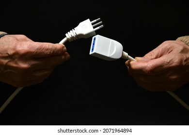 a man holds two disconnected electric cables in his hand on black background. electricity supply problem concept. blackout